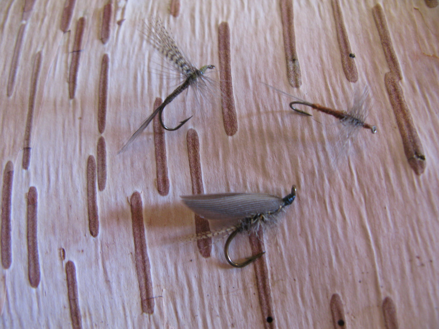 Tied flies. Clockwise from bottom: gold-ribbed hare's ear, traditional quill Gordon, and rusty spinner.